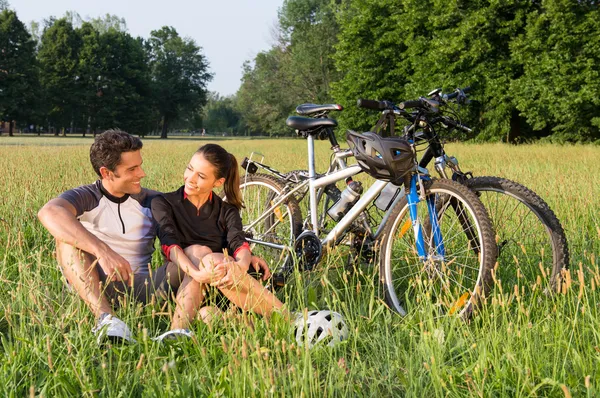Casal jovem de bicicleta no prado — Fotografia de Stock