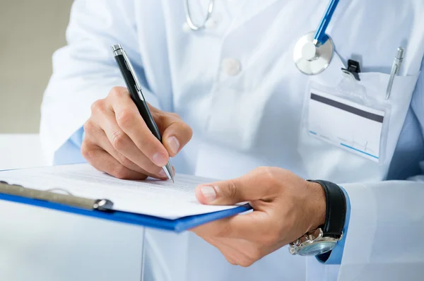 Male Doctor Writing On Medical Document — Stock Photo, Image