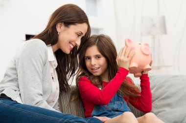 Anne kızı holding piggybank arıyorsunuz