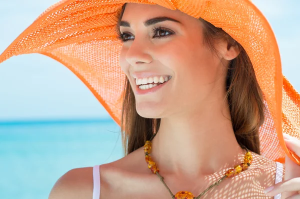 Giovane donna con cappello arancione al mare — Foto Stock