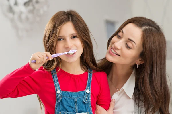 Дівчина з матір'ю чистити зуби — стокове фото