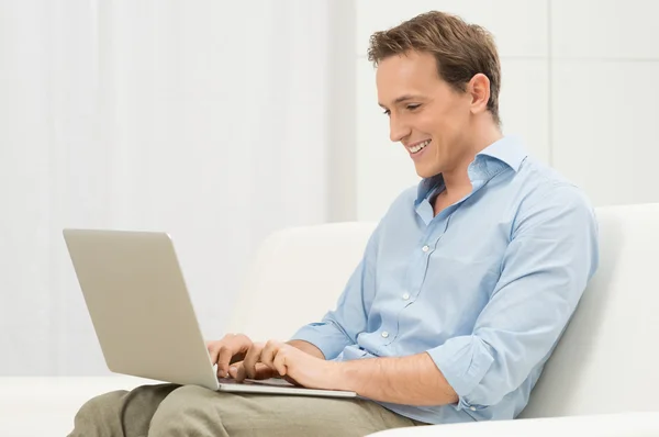 Mann auf Sofa mit Laptop — Stockfoto