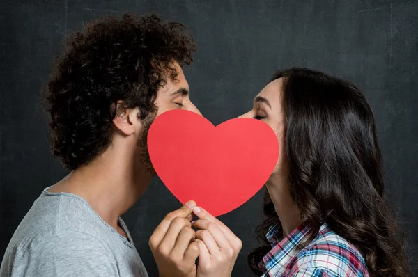 Пара поцелуев за бумажным сердцем — стоковое фото