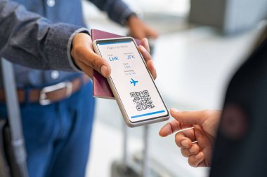 Telefonda uçuş görevlisine elektronik uçuş kartı gösteren melez bir yarışçının elini kapat. Hostes, giriş kapısında elektronik uçuş biletini kontrol ediyor. Tezgahta ve çevrimiçi uçak biletinde havalimanı kontrolü.