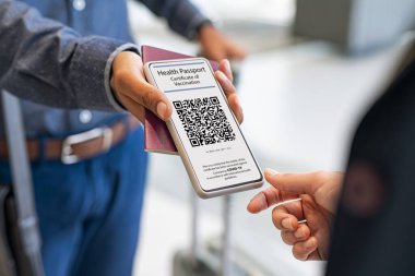 Hostese sağlık pasaportu gösteren melez adamın elini kapat. Hostes, biniş kapısında elektronik aşıyı kontrol ediyor. Tezgahta havaalanı kontrolü ve aşılama kontrolünün kanıtı..