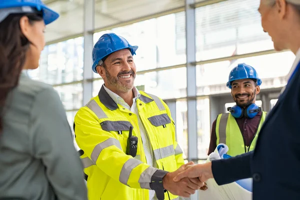 微笑的土木工程师与快乐的女商人在建筑工地握手 施工经理和主管在建筑工地握手 工人们通过握手达成协议 — 图库照片
