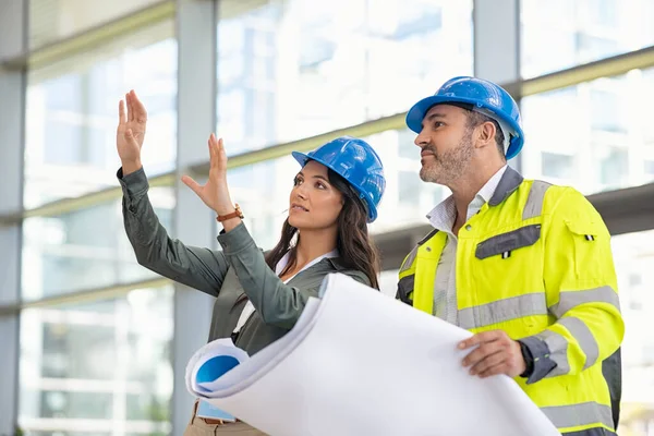 Ung Kvinnlig Arkitekt Som Förklarar Ritningen För Arbetsledaren Säkerhetsväst Byggarbetsplatsen — Stockfoto