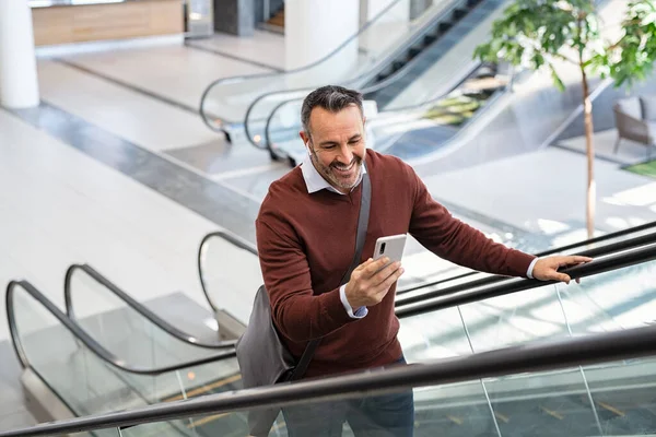 공항에서 스마트폰으로 메시지를 사업가에게 미소를 있습니다 일하러 스마트 사용하여 에스컬레이터에 — 스톡 사진