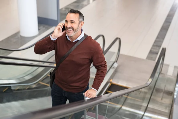 Sorridente Uomo Maturo Piedi Scala Mobile Mentre Parla Smartphone Aeroporto — Foto Stock