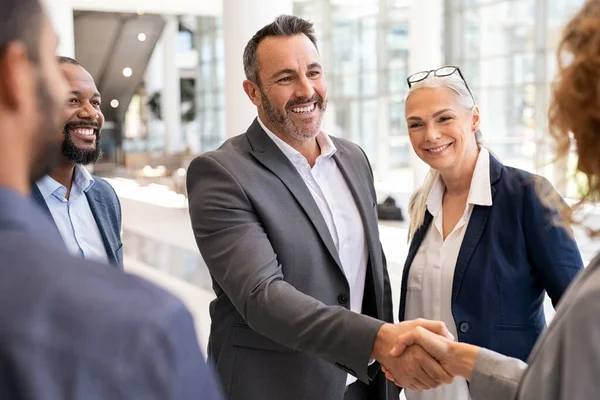 現代オフィスでビジネスウーマンと握手をする幸せな成熟したビジネスマン 起業家の握手でビジネスの女性を迎える成功 契約及び取引の概念 — ストック写真