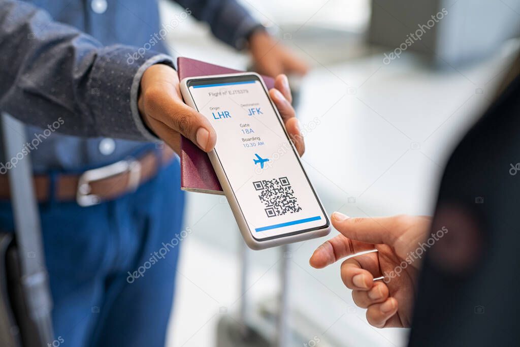 Close up hand of mixed race man showing electronic boarding pass to flight attendant on phone. Hostess checking electronic flight ticket at boarding gate. Airport check in counter and online air ticket.