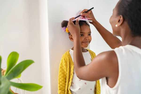 Madre Africana Mediana Edad Que Mide Altura Hija Marca Pared —  Fotos de Stock