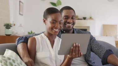 Dijital tablet kullanarak video görüşmesinde gülümseyen olgun çift el sallıyor. Orta yaşlı siyahi erkek ve kadın, dizüstü bilgisayarında aile veya arkadaşlarıyla görüntülü görüşme yapıyor. Orta yaşlı koca ve Afrikalı Amerikalı eş görüntülü konuşma yapıyor..