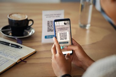 Kafeteryada parasız ödeme için QR kodunu tarayan genç bir kadının ellerini kapatın. Müşteri el yapımı ödemenin ayrıntıları akıllı telefon ve kafede tarama kodu ile. Afrikalı bir kadın akıllı telefonuyla yemek büfesinde soru cevap kodu ile ödeme yapıyor..