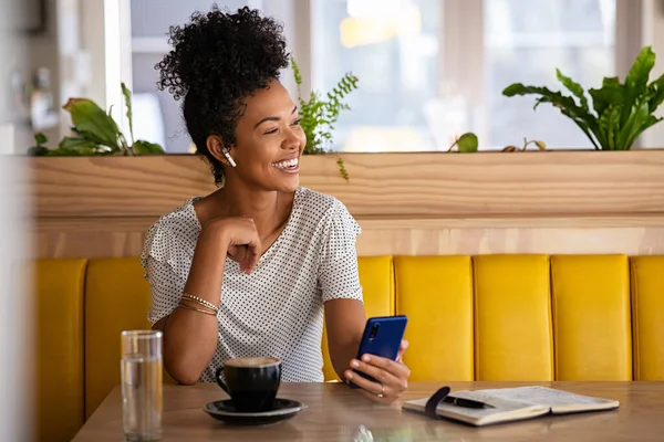 Kulaklıklı Gülümseyen Genç Bir Kadın Modern Kafede Telefon Tutup Kahve — Stok fotoğraf