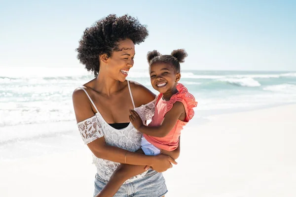 在暑假的海滩上开心地笑着妈妈和美丽的女孩 一个快乐的非洲裔美国女人在镜头前抱着可爱的小女孩的画像 黑人小孩在海滨拥抱她的姐姐 带着抄袭的空间 — 图库照片