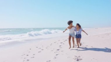 Gülümseyen siyah kadın sahilde en iyi arkadaşıyla eğleniyor. Latin Latin kökenli genç kadınlar tatilde deniz kıyısında yalınayak koşuyorlar. Neşeli arkadaşlar güneşli bir günde denizde eğleniyorlar..