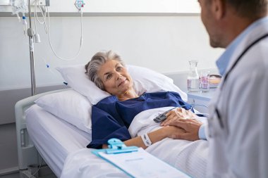 Doktor, yaşlı bir kadının hastane yatağında yattığını garanti ediyor. Mutlu yaşlı bir hasta, doktor sağlık durumunu bildirdikten sonra kendini rahatlamış hissediyor. Hastane doktoru, ameliyattan önce hastanede yatan yetişkin bir kadını muayene ediyor.