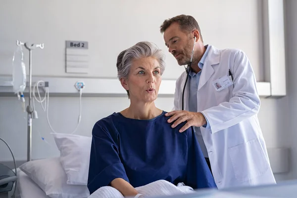 Lekarz Słuchający Starszej Kobiety Przez Stetoskop Hospitalizowana Starsza Kobieta Siedząca — Zdjęcie stockowe