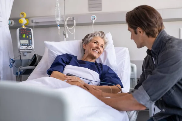 Filho Visitando Velha Mãe Doente Hospital Paciente Sênior Sorridente Conversa — Fotografia de Stock