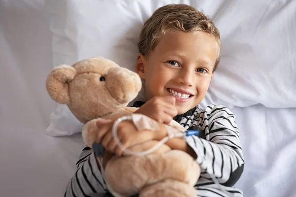 Menino Feliz Abraçando Ursinho Pelúcia Com Gotejamento Mão Sorrindo Cama — Fotografia de Stock