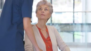 Tekerlekli sandalyedeki yaşlı kadınla ilgilenen kadın hemşire. Hastanedeki tekerlekli sandalyedeki yaşlı kadını önemseyen dost canlısı bir sağlık görevlisi. Huzurevinde bakıcısı olan mutlu yaşlı kadın..