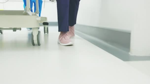 医院急诊室护士腿急促伸缩的密闭 医疗用品在医院走廊里推着Gurney 医生和护士急急忙忙跑到手术室的脚步声 — 图库视频影像