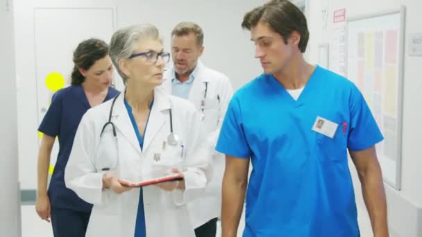 Ιατρική Ομάδα Που Περπατάει Βιαστικά Και Αλληλεπιδρά Στο Σύγχρονο Νοσοκομείο — Αρχείο Βίντεο