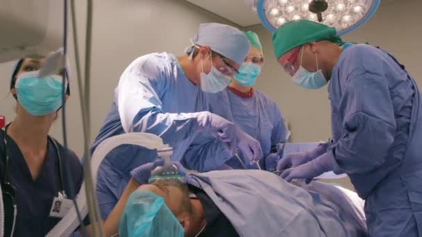 一组带着外科口罩的有经验的外科医生在手术室里一起工作 在手术室为病人做手术时戴防护帽和外科帽的专业外科医生医务人员 — 图库视频影像