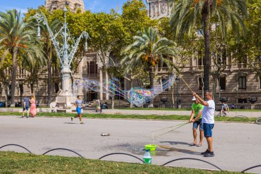 Barselona, İspanya - 20 Eylül 2021: İki adam yazın sonlarında Arc de Triomf yakınlarında sokaklarda dev sabun köpükleri yapıyor. Turistler fotoğraf için bağış yapar ve çocuklar mutlu olur.