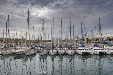 Barcelona, İspanya - 21 Eylül 2021: Barcelona Port Vell 'de yelkenli ve marina Rambla de Mar. Rıhtıma demir atan yelkenliler. Geminin direkleri bulutlu gökyüzüne kadar uzanıyor. Güvenli liman.