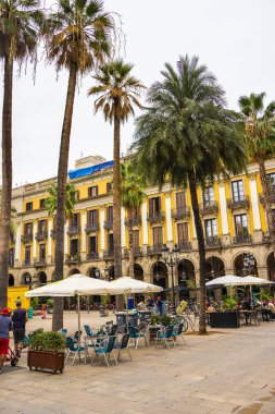 Barselona, İspanya - 23 Eylül 2021: Barcelona sokaklarındaki sokak kafesi. İnsanlar şemsiye altında oturup kahve ve şarabın tadını çıkarıyorlar. Rambla yakınlarındaki Plaza Reial 'dan şehir sokakları.