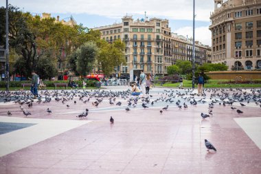 Barselona, İspanya - 22 Eylül 2021: Barcelona 'nın kalbi Katalunya Meydanı' na bakın. Turistler güvercinleri besliyor ve kuşların fotoğraflarını çekiyor. Meydanda binlerce hayvan yaşıyor..