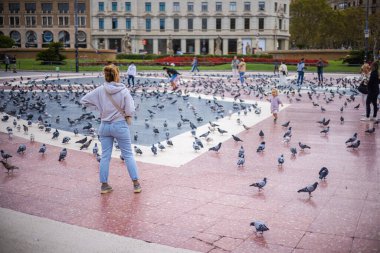 Barselona, İspanya - 22 Eylül 2021: Barcelona 'nın kalbi Katalunya Meydanı' na bakın. Turistler güvercinleri besliyor ve kuşların fotoğraflarını çekiyor. Meydanda binlerce hayvan yaşıyor..