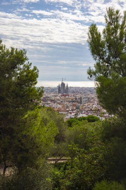 Barcelona, İspanya - 22 Eylül 2021: Castell de Montjuic 'ten Sagrada Familia' ya görüntü. Ağaçların arasından katedrale giden şehir manzarası. Şehrin turistik bölgesi. Hava Görünümü