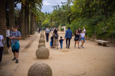 Barcelone, İspanya - 23 Eylül 2021: İnsanlar ve aileleri Park Guell 'de yürüyor ve yaz gününün tadını çıkarıyorlar. Parc Guell, bahçeler ve mimari elementlerden oluşan bir kamu park sistemidir.