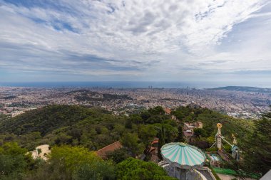 Barselona, İspanya - 22 Eylül 2021: Barcelona ufuk çizgisi üzerinde hava manzarası. Tibidabo Dağı 'nın zirvesinden geniş açılı panoramik görüntü. Ön planda Tibidabo Eğlence Parkı, ufukta deniz.