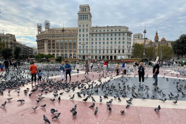 Barselona, İspanya - 22 Eylül 2021: Barcelona 'nın kalbi Katalunya Meydanı' na bakın. Turistler güvercinleri besliyor ve kuşların fotoğraflarını çekiyor. Meydanda binlerce hayvan yaşıyor..