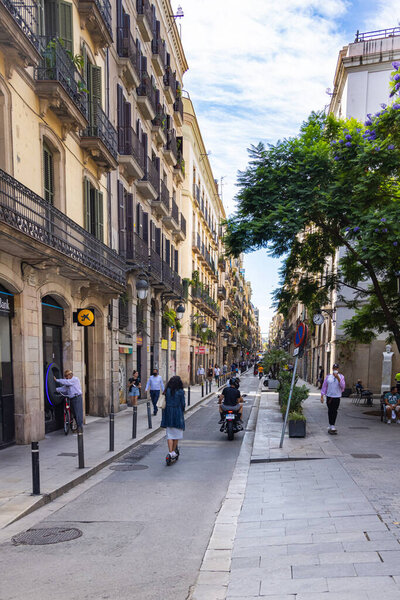 Barcelona, Spain - September 23, 2021: Cityscape of Barcelona. Typical architecture in the Catalan capital. Narrow streets and houses with narrow iron grate balconies. People walk on the streets.