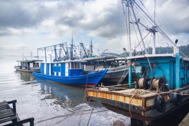 Sandakan, Malezya - 06 Ocak 2022: Sandakan, Borneo şehir merkezine yakın bir balıkçı köyü. Kıyıdaki sahil suyunda tahta bacaklı zavallı kulübeler. Rıhtımdaki balıkçı tekneleri. Limandaki gemiler