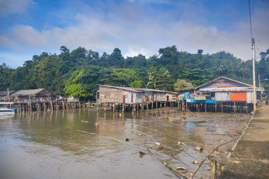 Sandakan, Malezya - 06 Ocak 2022: Sandakan, Borneo şehir merkezine yakın bir balıkçı köyü. Kıyıdaki sahil suyunda tahta bacaklı zavallı kulübeler. Plastik çöpler okyanusu ve sahili kirletiyor..