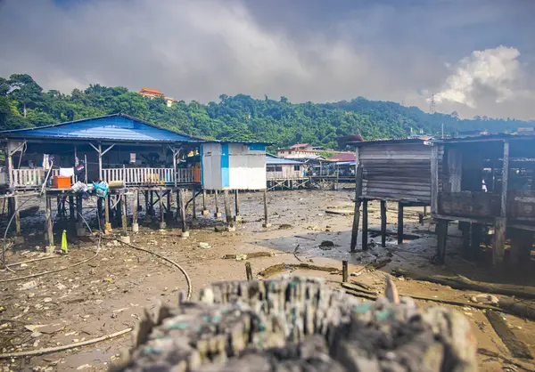 Sandakan, Malezya - 06 Ocak 2022: Sandakan, Borneo şehir merkezine yakın bir balıkçı köyü. Kıyıdaki sahil suyunda tahta bacaklı zavallı kulübeler. Plastik çöpler okyanusu ve sahili kirletiyor..