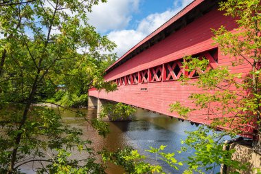 Wakefield, Quebec, Canada - August 30, 2021: Wakefield Covered Bridge crossing the river Gatineau. Wooden bridge in the rural Quebec landscape. The riverbank invites you to swim in the cold water