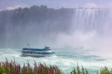 Niagara Falls, Canada - August 27, 2021: The Maid of Mist at the Ontario Side of the Niagara Falls. One of the Tourist attractions at the huge water falls. Tourists getting wet during the boat ride.