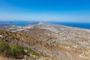 Yunanistan 'ın Santorini, Cyclades takımadasındaki en popüler adanın panoramik açıdan geniş açılı görüntüsü. Mavi Ege Denizi ufukta, beyaz evler kuru kahverengi manzaralar arasında. Hava görünümü