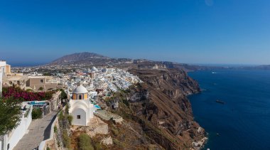 Santorini, Yunanistan - 7 Ağustos 2021: Ege Denizi 'ndeki Cyclades takımadasındaki Santorini' nin tipik evlerinin çatılarına bakın. Mavi gökyüzünün altındaki Beyaz Saray. Uçurumun tepesindeki köy