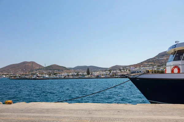 Paros, Greece - August 8, 2021: Tugboat moored at the pier of Paros. Boat guides the ferries and cruise ships into the port. The village of Paros in the background. Town in the cyclades archipelago