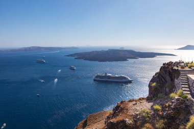 Yunanistan 'ın Santorini Körfezi' ne bakın. Ege Denizi 'ndeki Cyclades takımadalarında. Küçük adadaki turistlere su getiren yolcu gemileri körfeze yanaştı. Denizin üzerindeki uçurumda