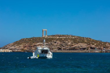 Naxos, Yunanistan - 6 Ağustos 2021: Arka planda Apollo Portara Tapınağı olan Naxos Körfezi 'nde özel bir yat. Ege Denizi 'ndeki Cyclades takımadalarında yer alıyor. Tarihi Yunan Harabeleri