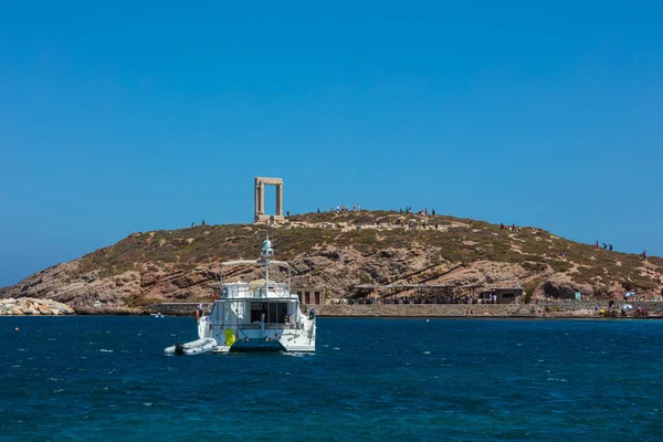 Naxos, Yunanistan - 6 Ağustos 2021: Arka planda Apollo Portara Tapınağı olan Naxos Körfezi 'nde özel bir yat. Ege Denizi 'ndeki Cyclades takımadalarında yer alıyor. Tarihi Yunan Harabeleri